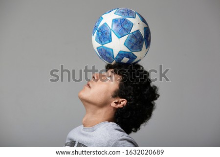 Portraits of a young fan practicing freestyle football on gray studio background