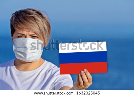 Woman in surgical face mask holds Russian flag. In Russia confirmed people infected with Wuhan Coronavirus disease COVID-19. Concept of spread of Chinese Corona virus disease COVID-19 around world