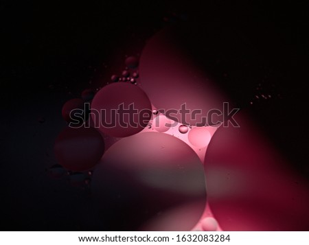 Black-pink oil bubbles in water surface with pink light blurred background ,macro drops, black abstract space background ,sweet color oil droplets ,shapes circles on the water ,selective focus