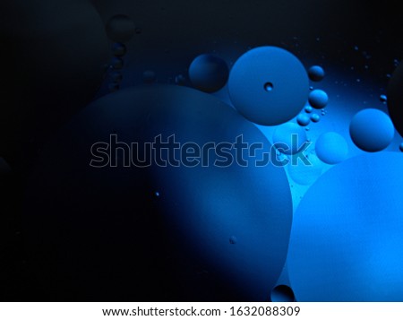 Closeup oil bubbles in water with black blue light blurred background ,macro image ,dark droplets abstract for card design