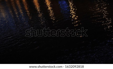 Magic night scenery. Concept. Close-up of pond dark water surface during the night with reflection from city lights.