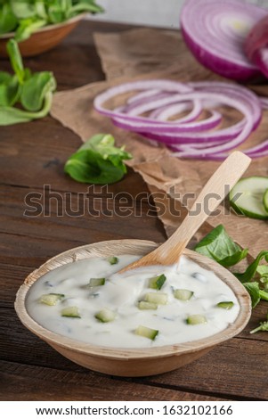 Top view of wooden cutting board on old wooden table top with tablecloth and yogurt sauce dip in a bowl