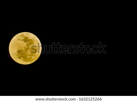 A landscape shot of a yellow full moon with black color in the background
