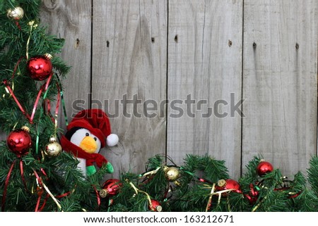Green garland border with ornaments and penguin on wooden fence