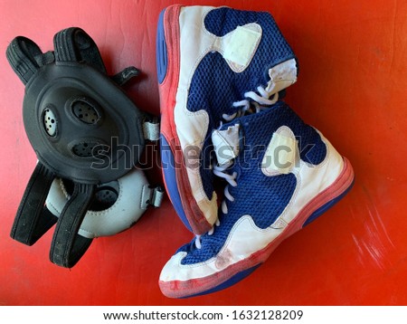 Wrestling shoes and headgear on a wrestling mat. Royalty-Free Stock Photo #1632128209