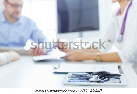 Doctor in clinic asking senior woman in wheelchair for a signature