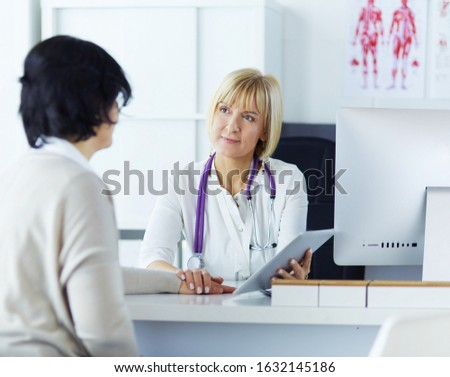 Female doctor using digital tablet talking with patients