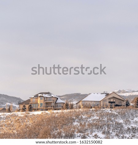 Photo Square frame Houses on residential area nestled on hills blanketed with snow in winter