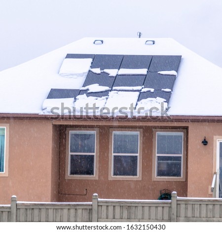 Photo Square frame Facade of home with solar panels on snowy roof against cloudy sky in winter