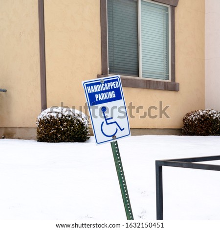 Photo Square frame Handicapped Parking sign and wheelchair ramp at a snowy parking lot in winter