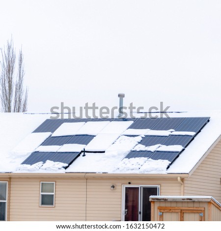 Photo Square frame Snow covered roof of home with solar panels against cloudy sky in winter