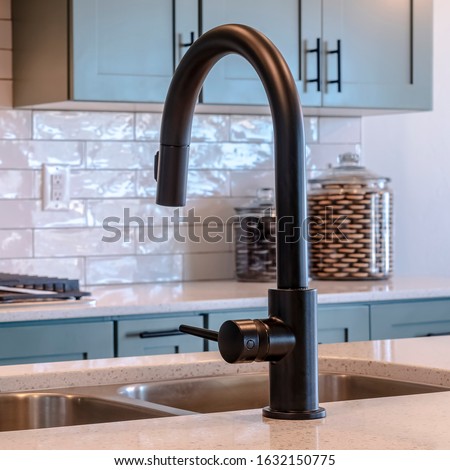 Photo Square frame Black faucet and double bowl kitchen island sink against cooktop and cabinets