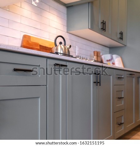 Photo Square Kitchen cabinets with white countertop black handles and tile backsplash