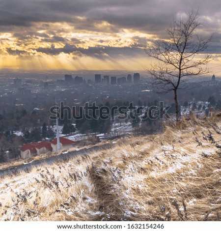Photo Square frame Golden setting sun and dark cloudy sky over downtown Salt Lake City in winter