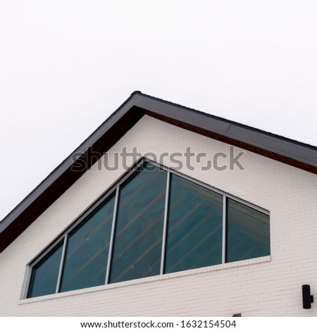 Photo Square frame Home exterior with tringular window and white wall under gable roof