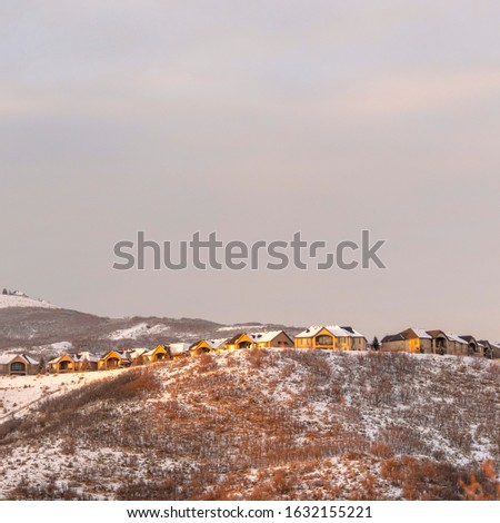 Photo Square frame Homes on hill with panoramic view of snowy terrain and natural beauty at sunset