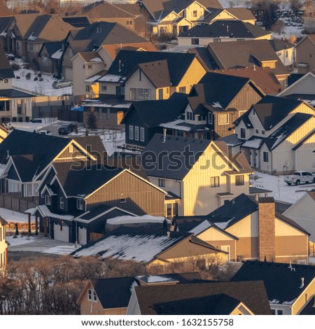 Photo Square Houses with snowy roofs and snowy yards illuminated by sunlight in winter