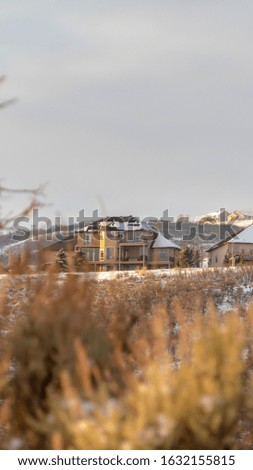 Photo Vertical frame Homes with snowy roofs on top of frosted hills against cloudy sky in winter