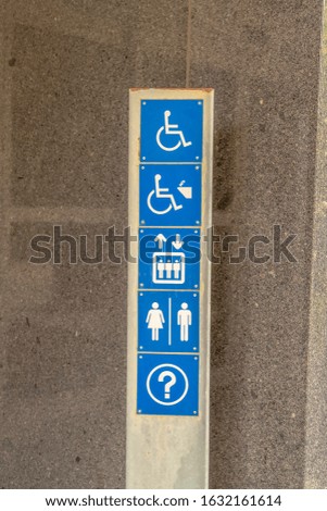 Various signages on a metal plate against the exterior wall of building