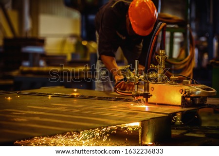Acetylene torch semi-auto machine cutting metalwork fabrication with bright sparks in factory. Royalty-Free Stock Photo #1632236833