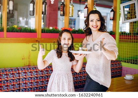 Beautiful mother with daughter. Family in a cafe. Girl with a dessert