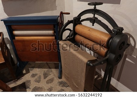 Two vintage mechanical mangles or wringers, also called clothes press,  placed in corner of large hall.  Royalty-Free Stock Photo #1632244192