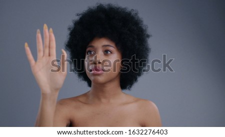 Smiling beautiful afro-american woman with curly hair working with digital virtual screen. Portrait of attractive ethiopic topless girl using technology isolated on grey background.