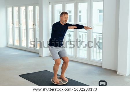 Man doing balance and muscle control exercises in a bright spacious urban gym in a health and fitness concept