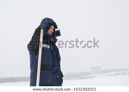 Builder with a shovel on the background of a frozen river