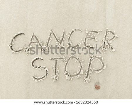 "Cancer Stop" written on sand. 