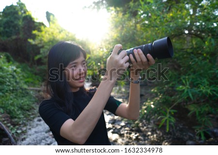 Asian woman photographer in nature. Taking pictures right side