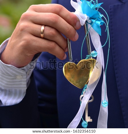 Lock with keys in the shape of a heart, golden metal, in a man's hand, close up.Wedding heart's. valentines card invitation. Valentines day background.Wedding ring on the finger.Holiday.
 