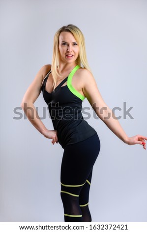 The concept of effective fitness. Full-length vertical photo of a pretty slender blonde woman athlete in a sports suit on a white background. Standing in different poses with emotions and a smile.