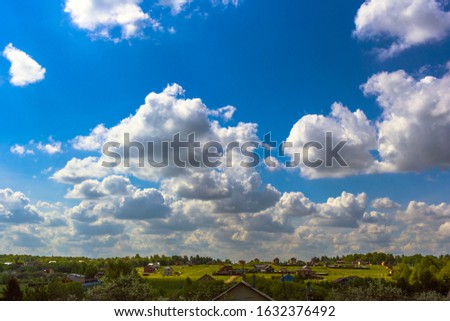 White fluffy clouds in the blue sky in beautiful day.Landscape of village and forest