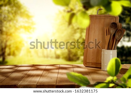 Brown wooden table cover of shadows and blurred background of garden.Sunny spring day and green leaves on branch decoration.Copy space for your product.