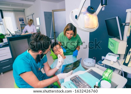 Male and female dentists showing a young boy patient his teeth x-ray image in the dental office.