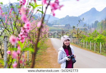 Asian girl with camera near flower plant.