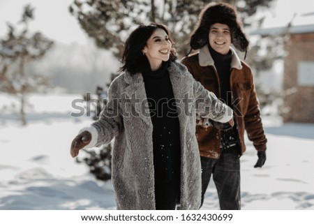 young beautiful couple guy and girl having fun outdoors in the park in winter