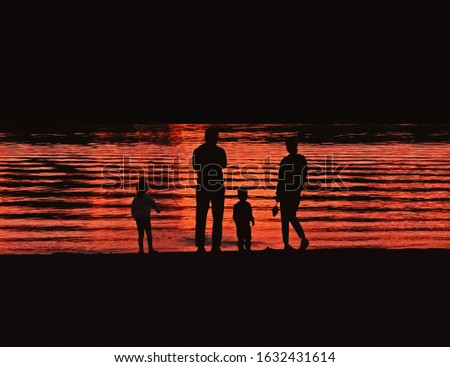 Silhouettes of people resting on the beach at sunset background.
