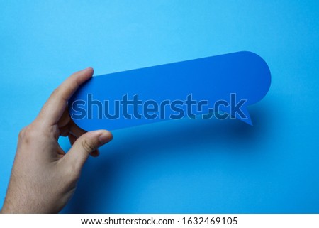 Man holding blank blue speech bubble on blue background.