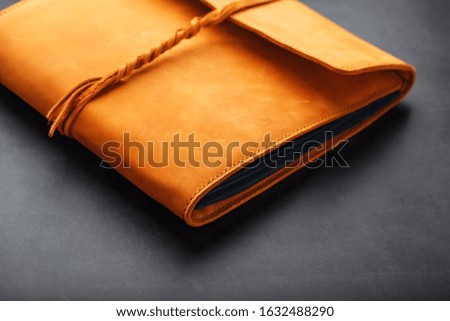 The leather cover of the album is made of brown handmade genuine leather on a black background. Elements of a leather product close-up.