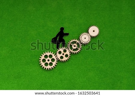 Silhouette of a man climbing up the gears on a green background. Business concept, promotion.