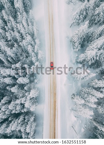 Car driving on winter mountain road. Beautiful aerial view with the trees covered in snow. Location: Rarau Mountains, Romania