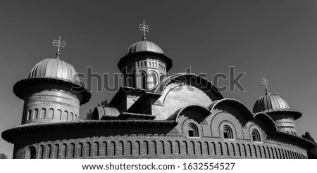 Orthodox dome with crosses. Orotodox style church and a blue sky. New Archbishop and Royal Cathedral of the Court of Arges. Royal house of Romania. The facade is made of brick. Black and white picture
