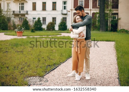 Cute couple in a park. Lady in a white blouse. Guy in a green sweater