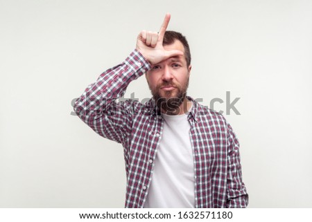 I am loser. Portrait of frustrated bearded man in casual plaid shirt showing loser gesture with L finger symbol, unhappy about failure, lost job. indoor studio shot isolated on white background