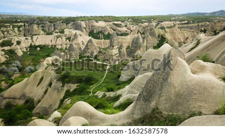 The wonderful nature of Urgup with lots of stone caves through the valley. A mushroom rocks, also called rock pedestals, or Fairy chimneys at the valley near Urgup, Cappadocia, Turkey.  Royalty-Free Stock Photo #1632587578