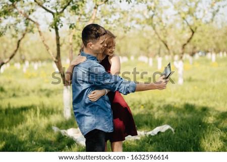 Cute couple in a park. Lady in a red dress. Boy in a blue shirt