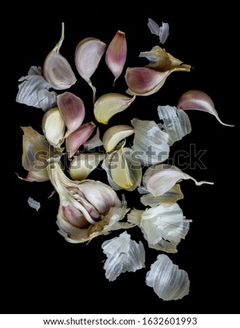 A vertical picture of garlic cloves under the lights against a black background