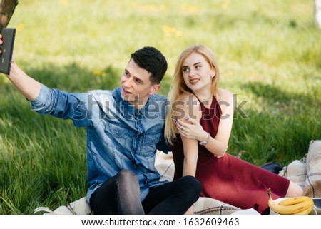 Cute couple in a park. Lady in a red dress. Boy in a blue shirt